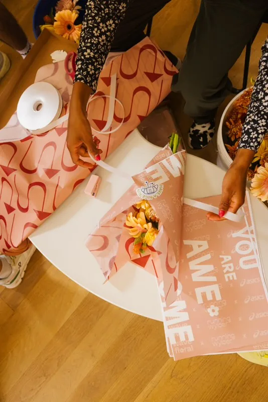 Finishing a wrapped bouquet with ribbon and a Running Wylder sticker