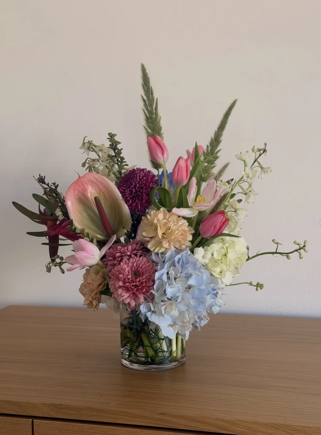 Pastel arrangement with blue hydrangea, pink tulips, anthurium and stock