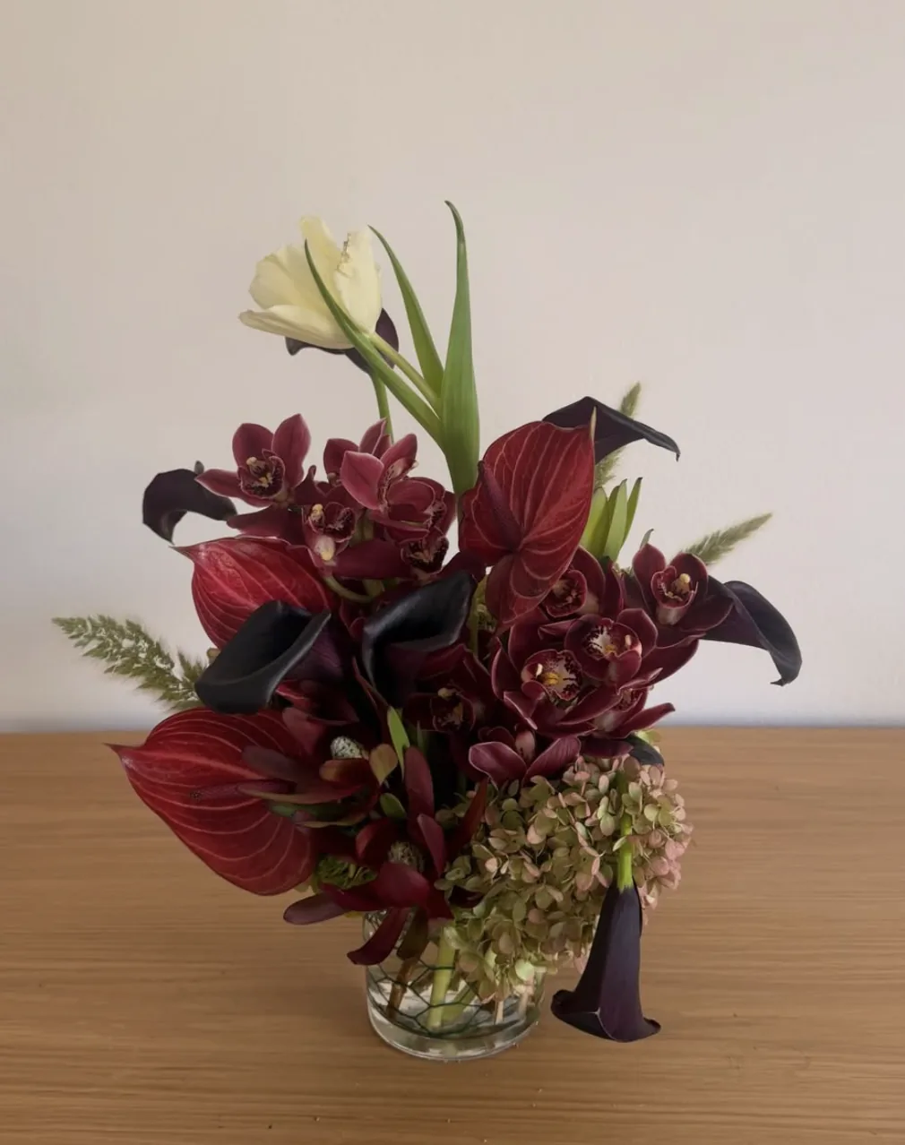 Moody burgundy arrangement with black calla lilies, anthurium and cymbidium orchid