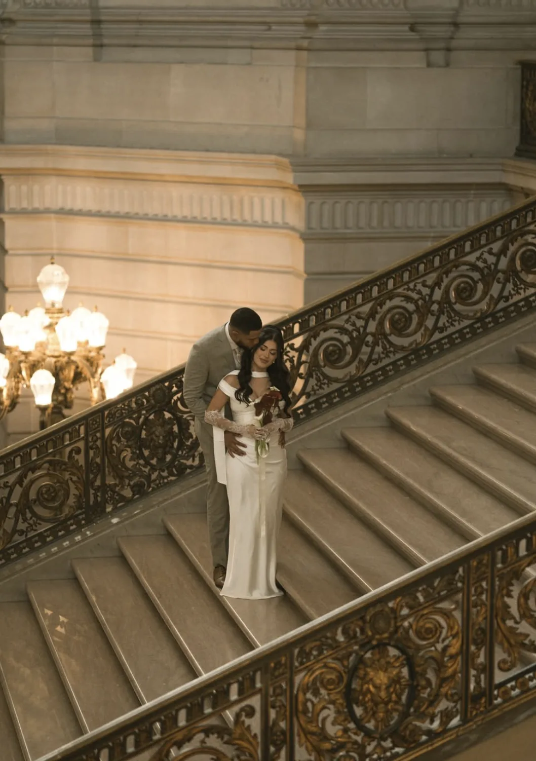 Couple on the San Francisco City Hall staircase with a burgundy calla lily bouquet