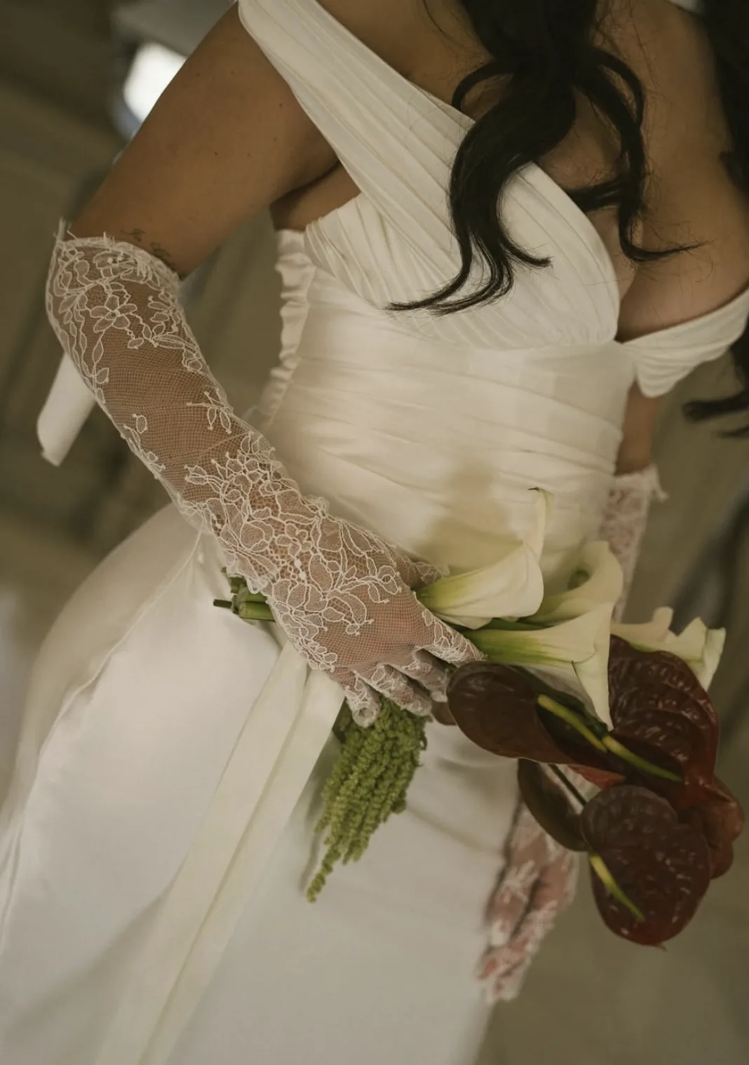 Bride in lace gloves holding white calla lilies, burgundy anthurium and green amaranthus