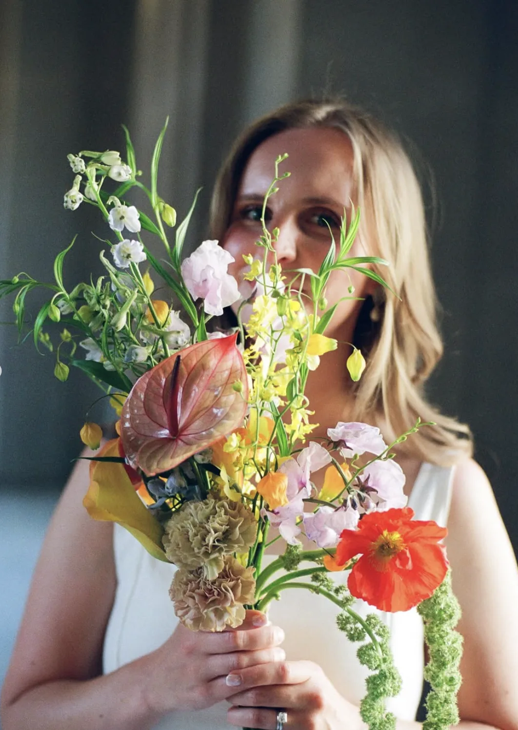 Bride holding a wildflower bouquet of Icelandic poppy, anthurium, sweet pea and hanging amaranthus