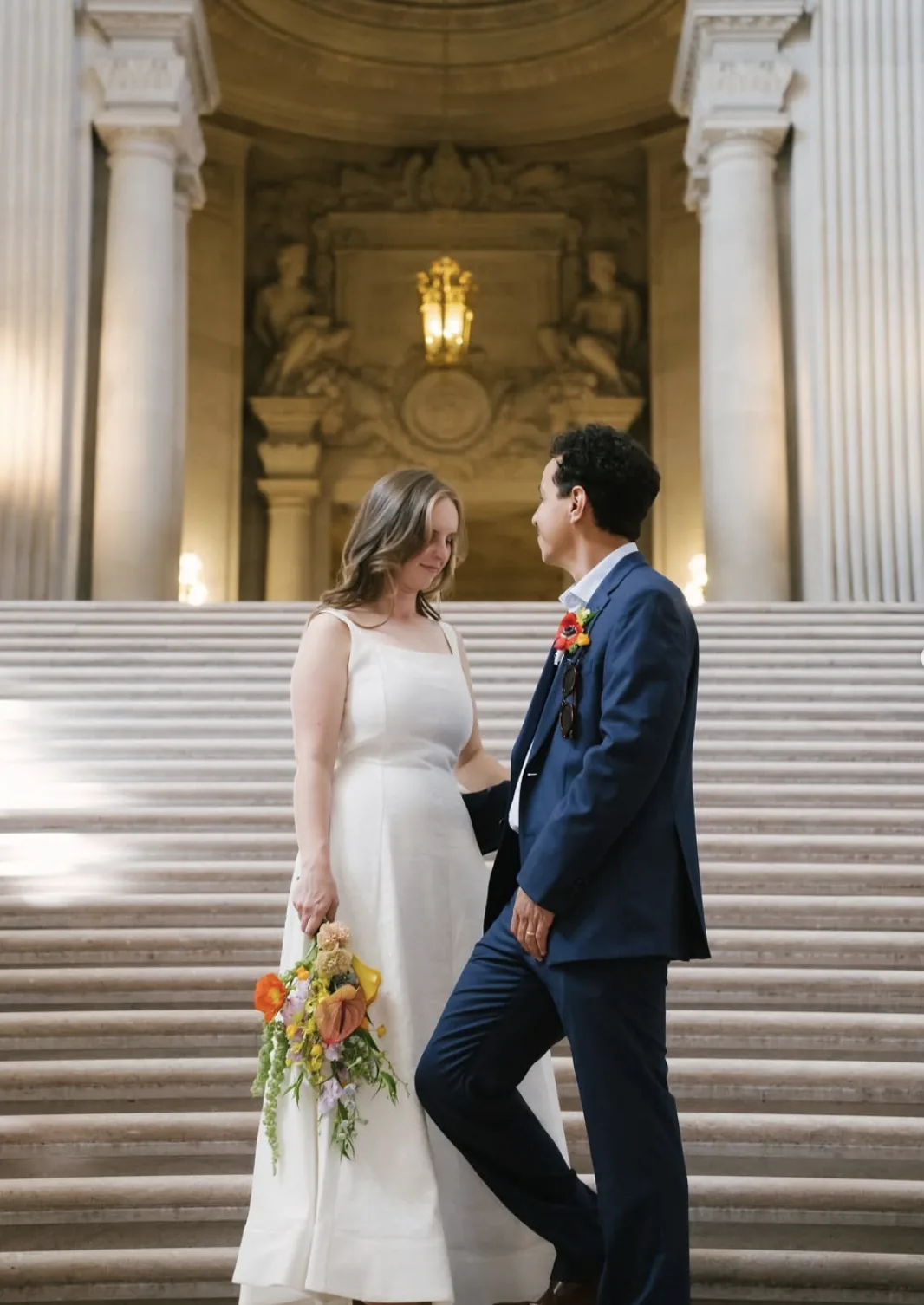 Couple on the San Francisco City Hall grand staircase with a bright wildflower bouquet