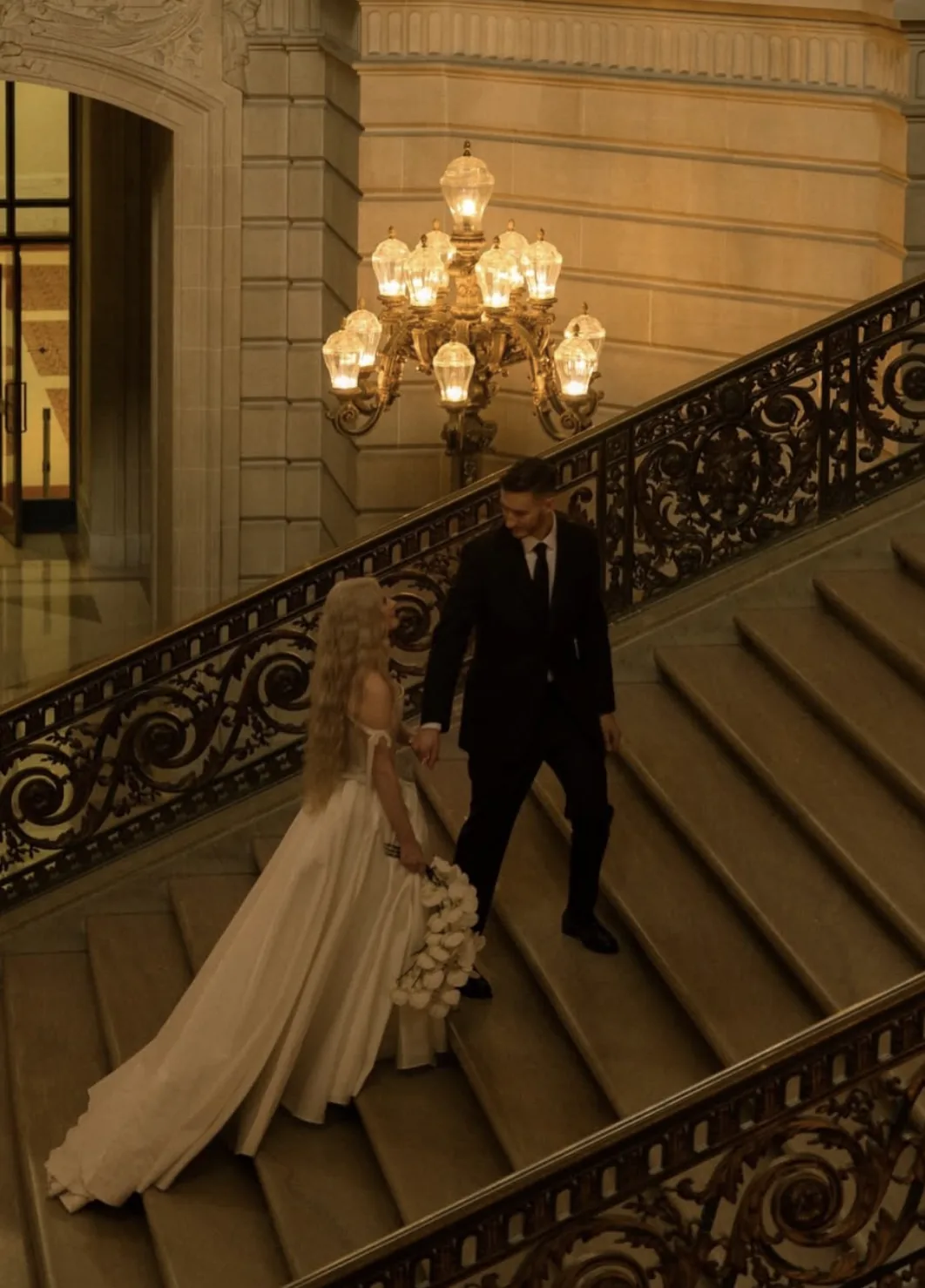 Couple on the City Hall staircase with a white orchid cascade bouquet
